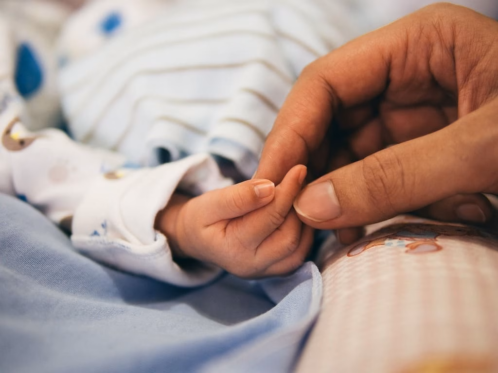 Madre con bebe en la cama, solo las manos
